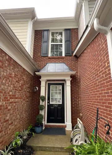 Front entrance of a red brick townhouse with black door and white trim
